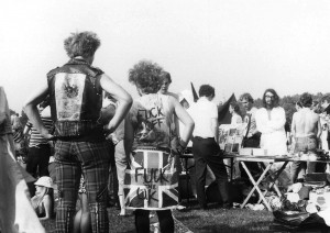 Punk wearing a British flag with 'Fuck the UK' written on it standing in front of a book stall at a protest for nuclear disarmament, UK, 1980s. © Stephen Cassidy _ Museum of Youth Culture